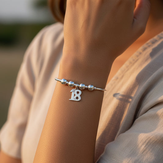 Model wearing a 18th Birthday charm girl's sterling silver stacking bracelet by My Silver Wish