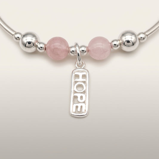 Closeup of "Hope" rose quartz healing crystal women's silver stacking charm bracelet by My Silver Wish