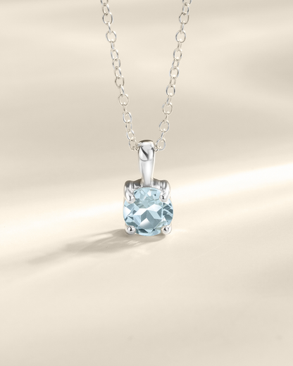 Silver necklace with a blue gemstone pendant on a beige background