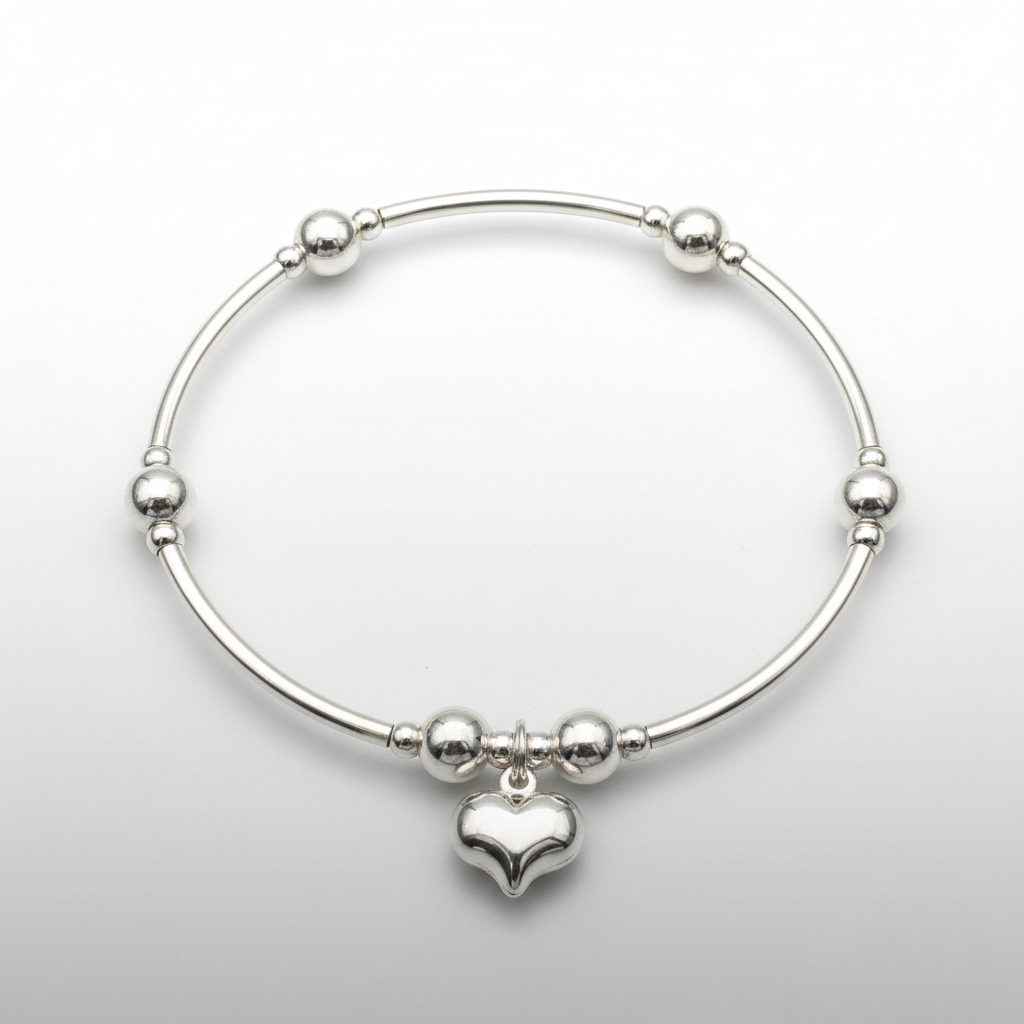 Silver bracelet with a puff heart charm on a light gray background