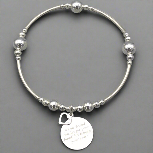 Silver bracelet with a heart-shaped tag on a gray background