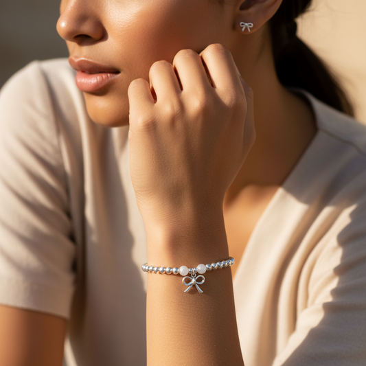 Model wearing a Ribbon Bow charm sterling silver hand-made women's stacking bracelet and earring gift set by My Silver Wish