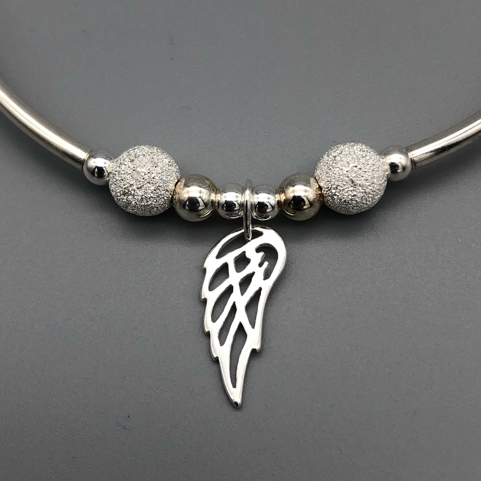 Closeup of Angel wing charm women's sterling silver stacking bracelet by My Silver Wish