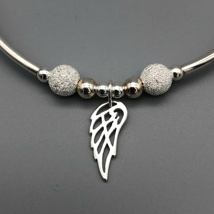 Closeup of Angel wing charm women's sterling silver stacking bracelet by My Silver Wish
