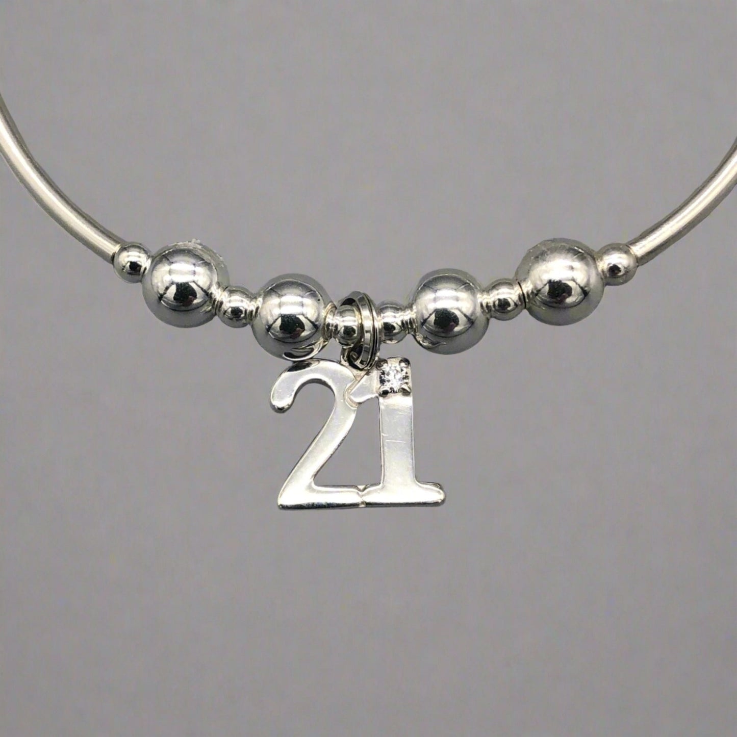 Closeup of 21st Birthday charm women's sterling silver stacking bracelet by My Silver Wish