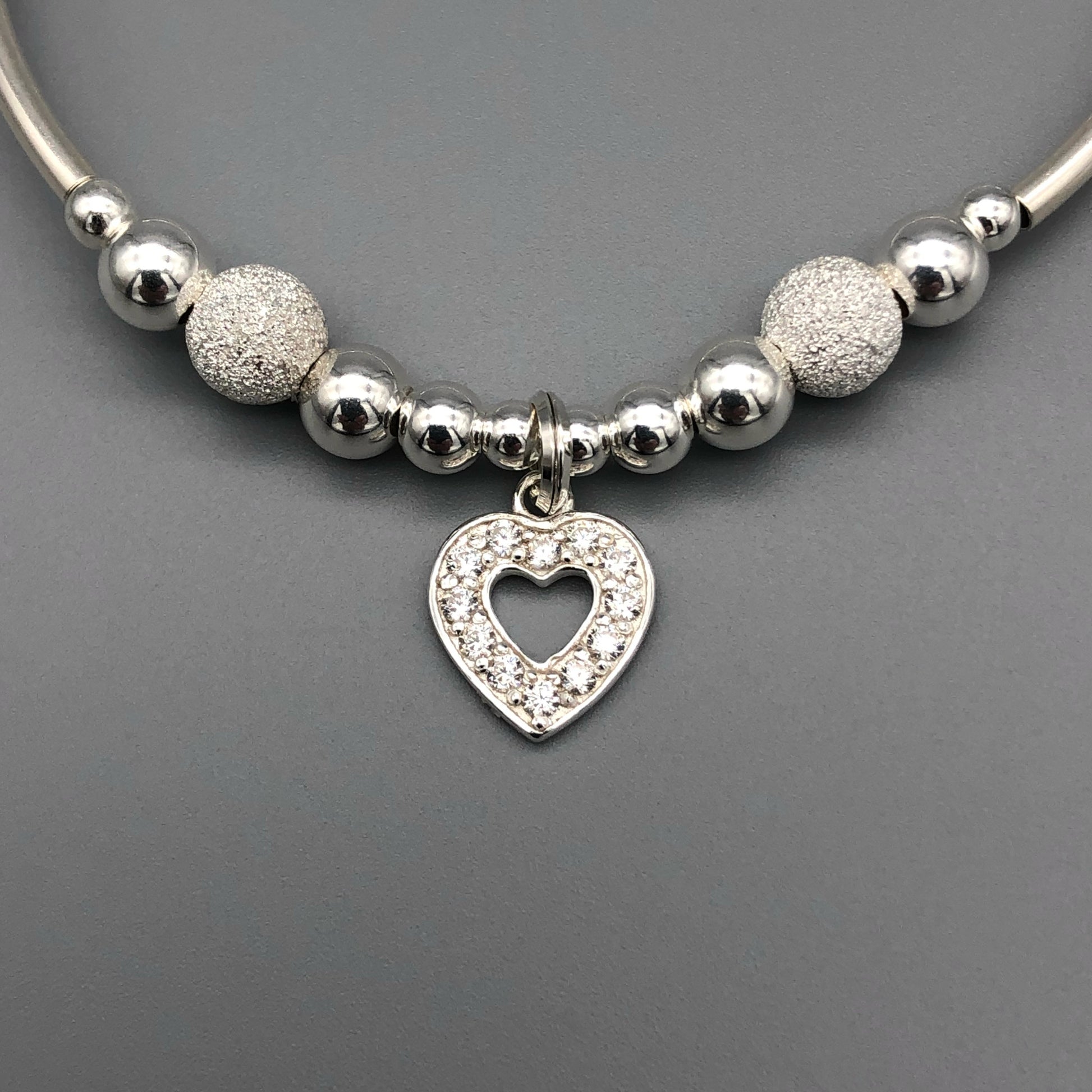 Closeup of Diamond heart charm starburst beads sterling silver hand-made women's stacking bracelet by My Silver Wish