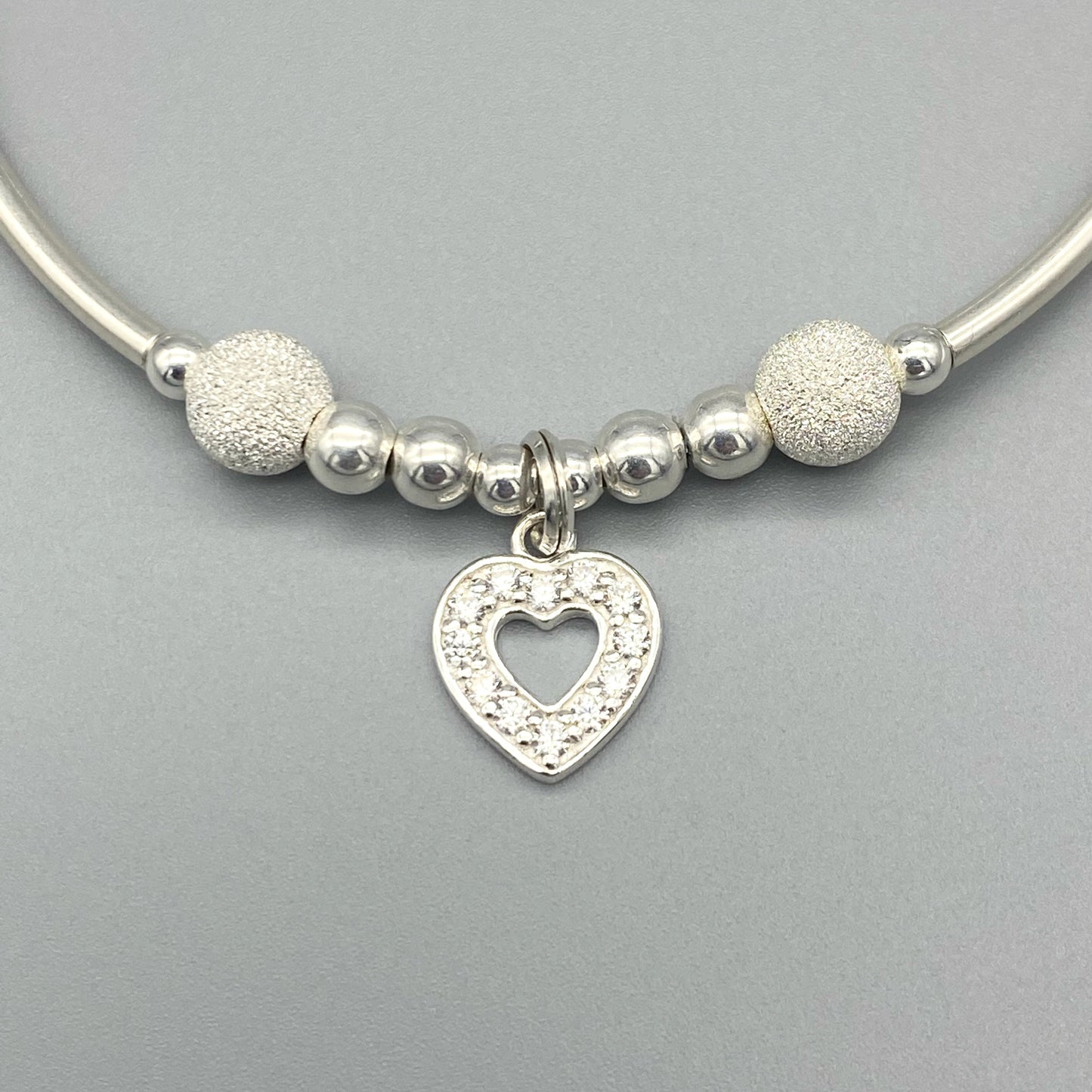 Closeup of Diamond heart charm and starburst beads women's sterling silver stacking bracelet by My Silver Wish