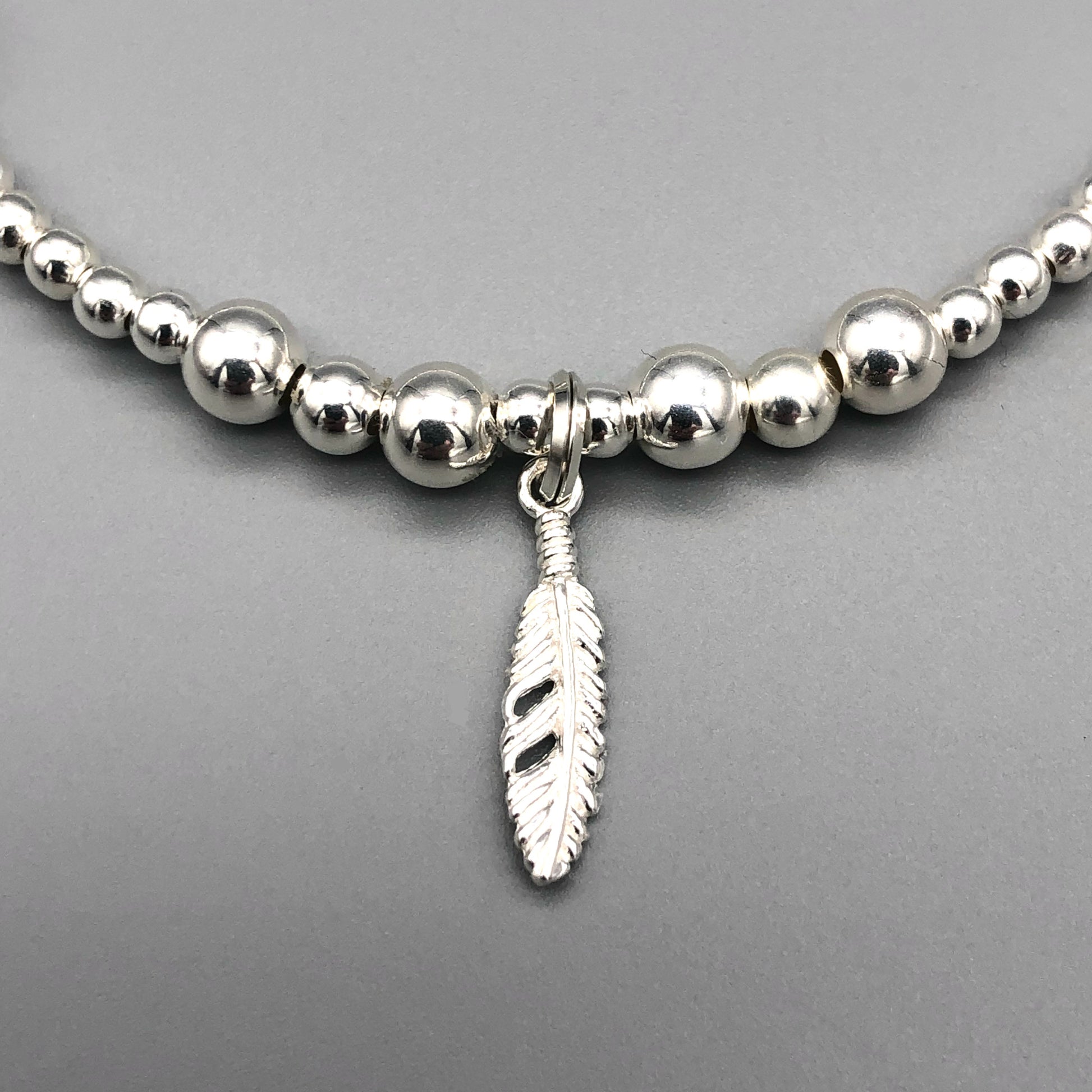 Closeup of Feather charm sterling silver stacking charm bracelet by My Silver Wish