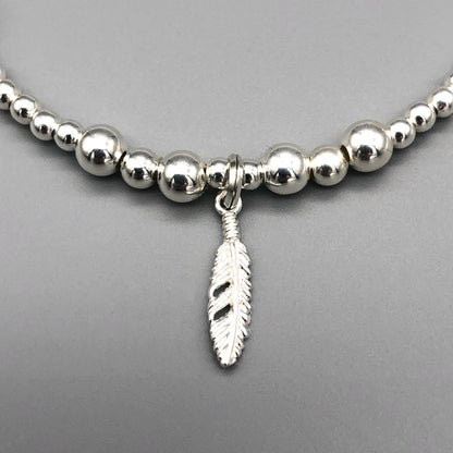 Closeup of Feather charm girl's 925 sterling silver stacking bracelet by My Silver Wish