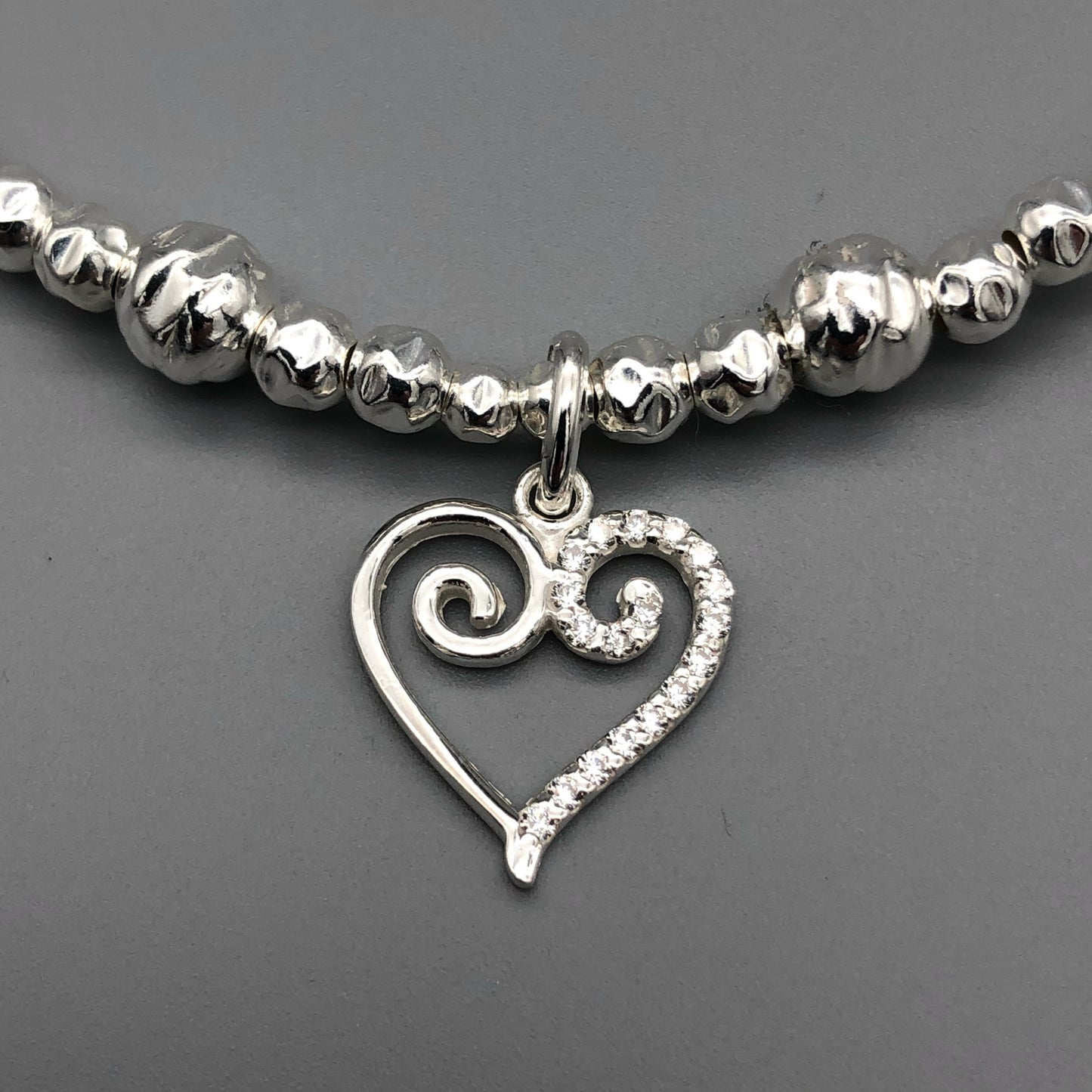 Closeup of Scroll heart charm sterling silver hand-made women's stacking bracelet by My Silver Wish