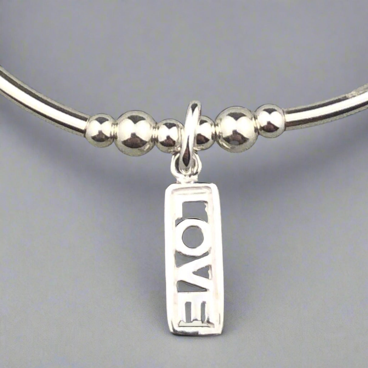 Closeup of "Love" rainbow & sterling silver women's stacking charm bracelet by My Silver Wish