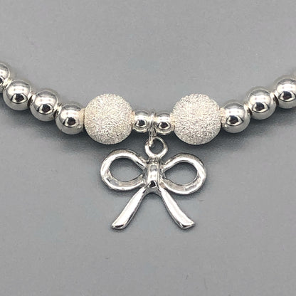 Closeup of Ribbon bow charm children's sterling silver stacking bracelet by My Silver Wish