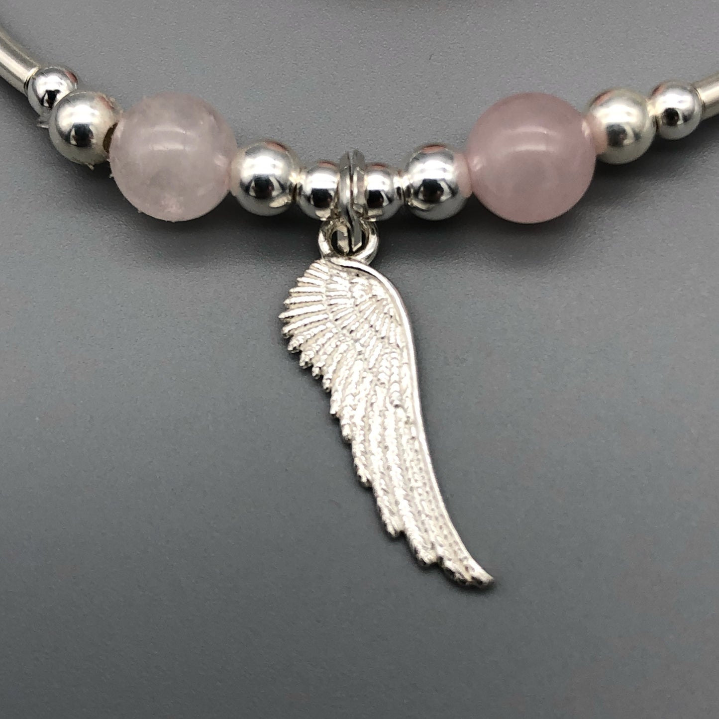 Closeup of Angel wing charm & rose quartz sterling silver stacking bracelet by My Silver Wish