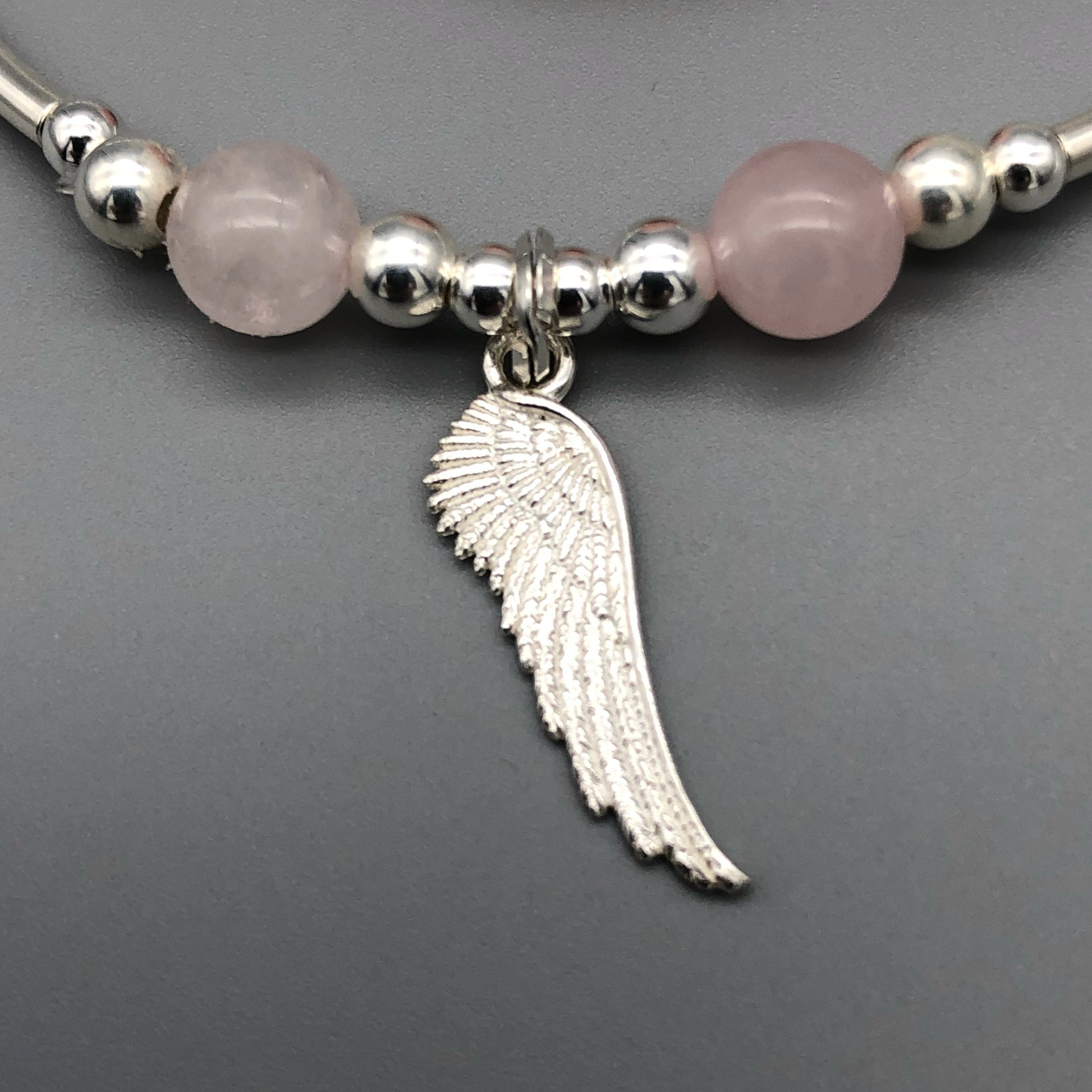 Closeup of Angel wing charm & rose quartz sterling silver stacking bracelet by My Silver Wish