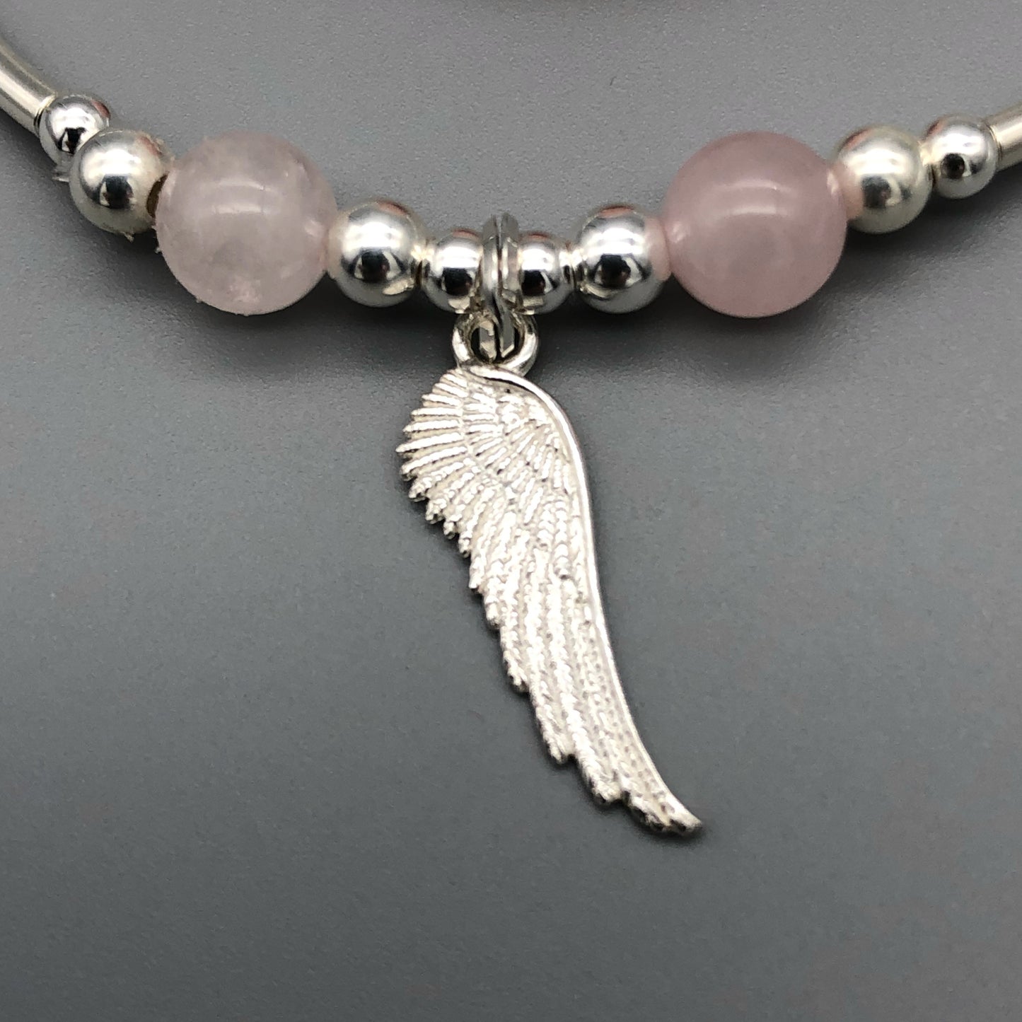 Closeup of Angel wing charm rose quartz & sterling silver stacking bracelet by My Silver Wish