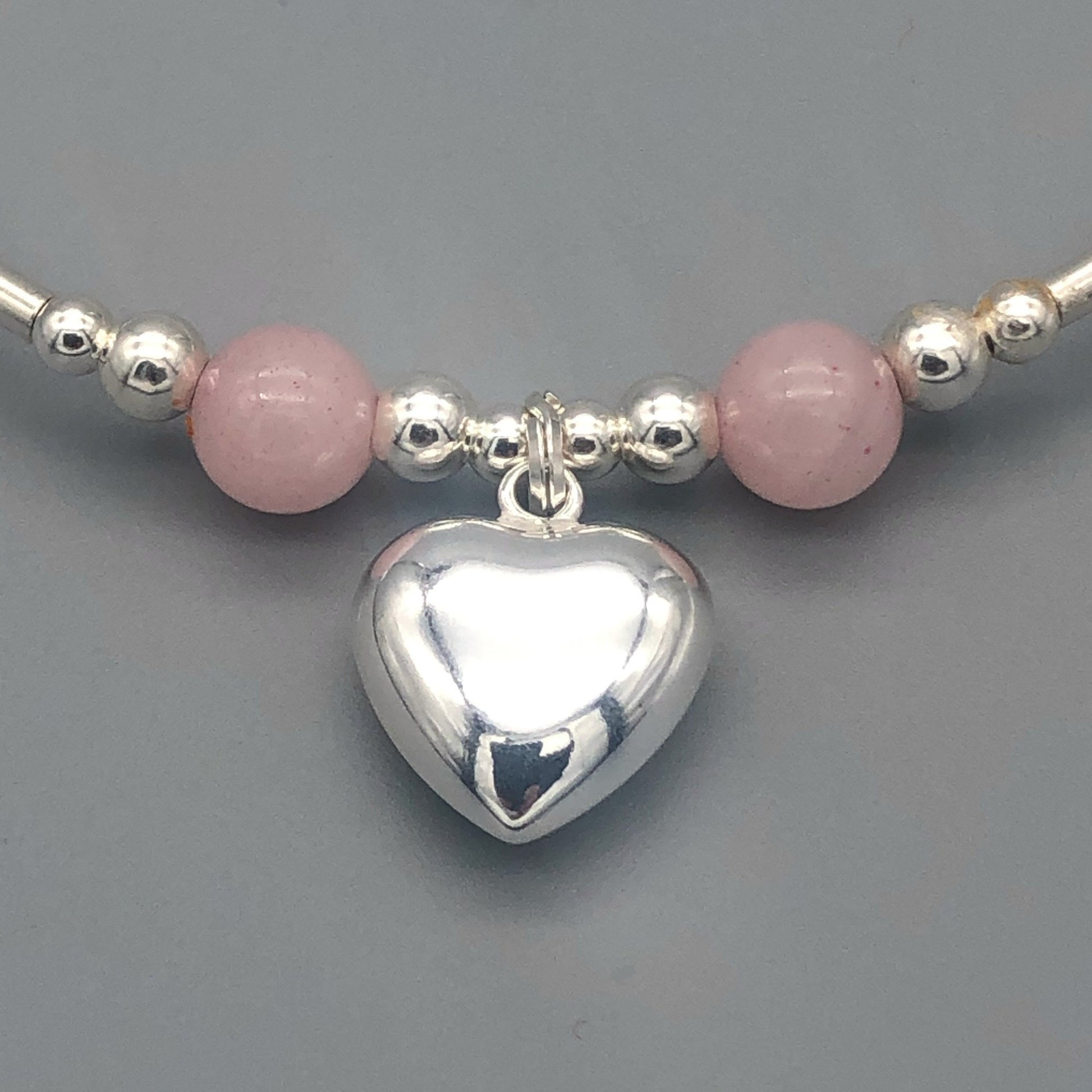 Closeup of Rose quartz solid heart charm sterling silver girl's stacking bracelet
