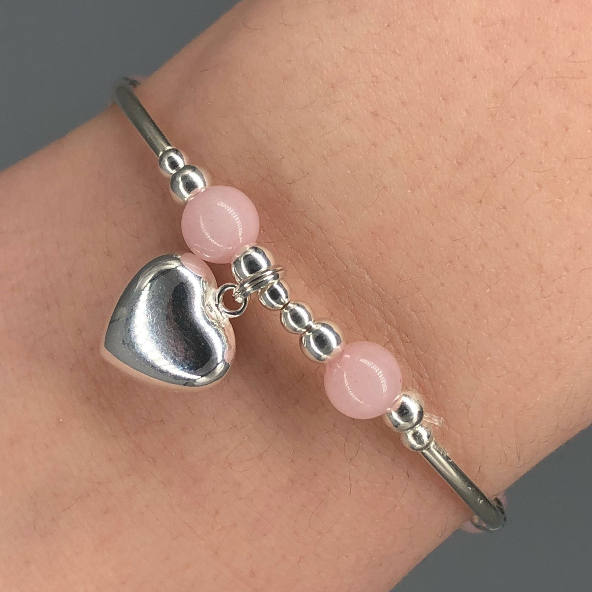 Closeup of Rose quartz solid heart charm sterling silver girl's stacking bracelet
