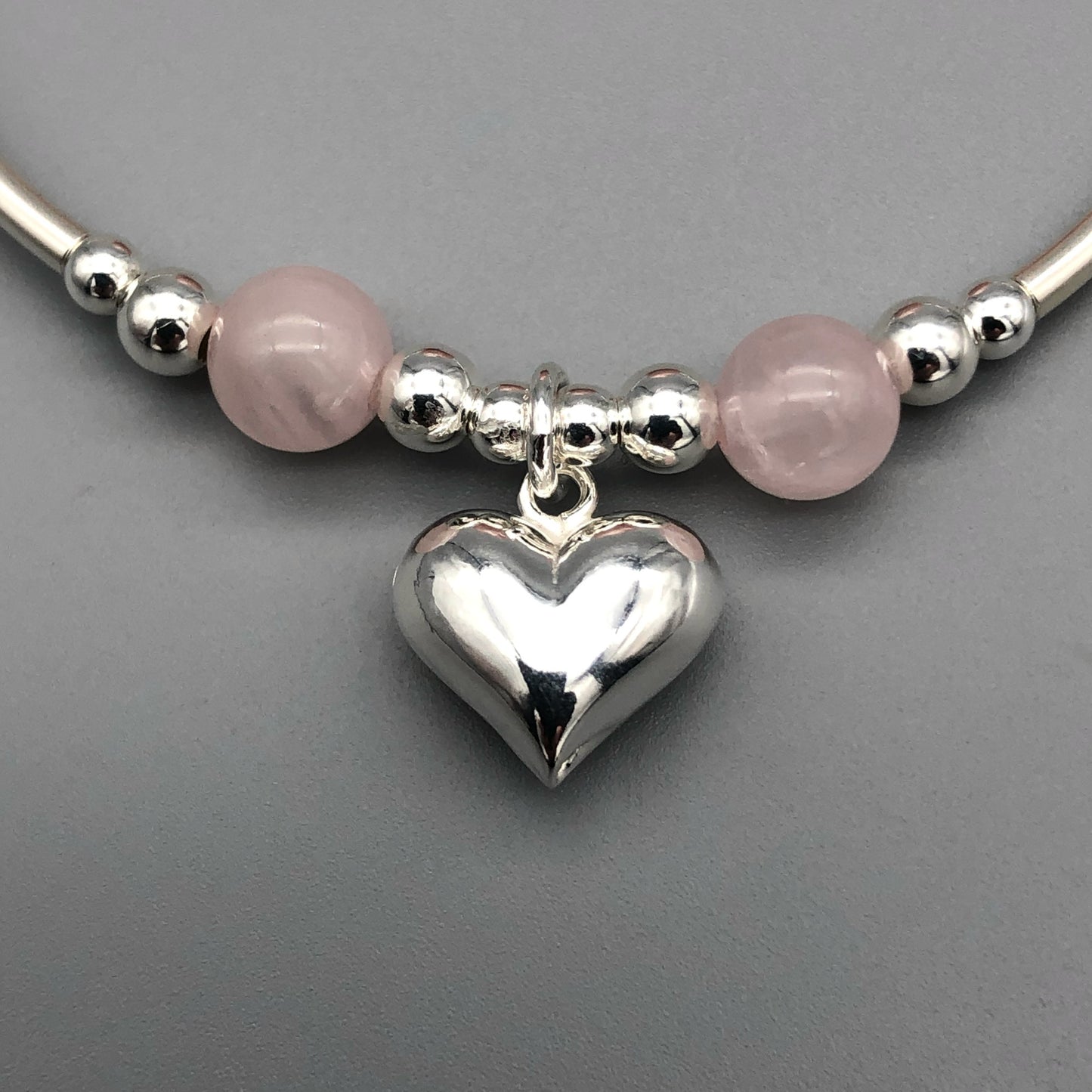 Closeup of Rose quartz puff heart charm sterling silver women's stacking bracelet by My Silver Wish