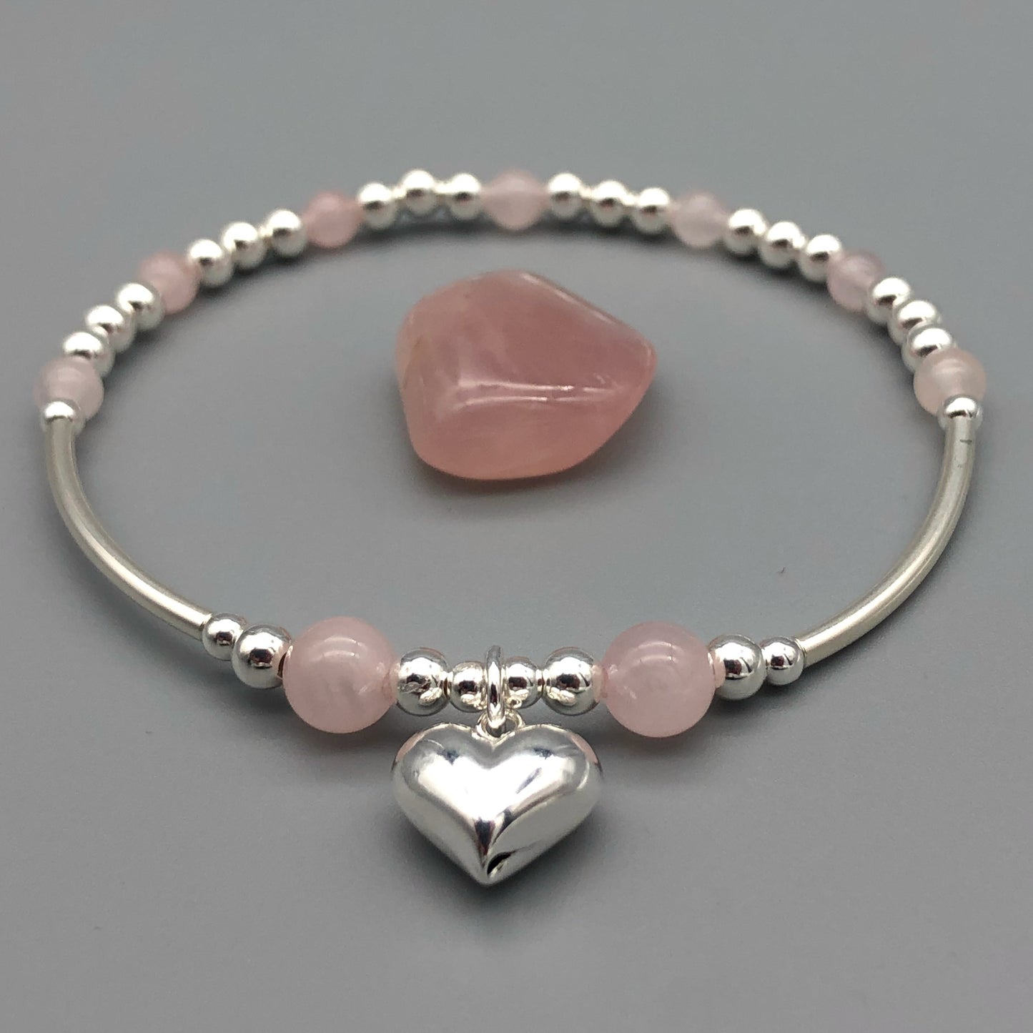 Clseup of Rose quartz puff heart charm sterling silver women's stacking bracelet by My Silver Wish