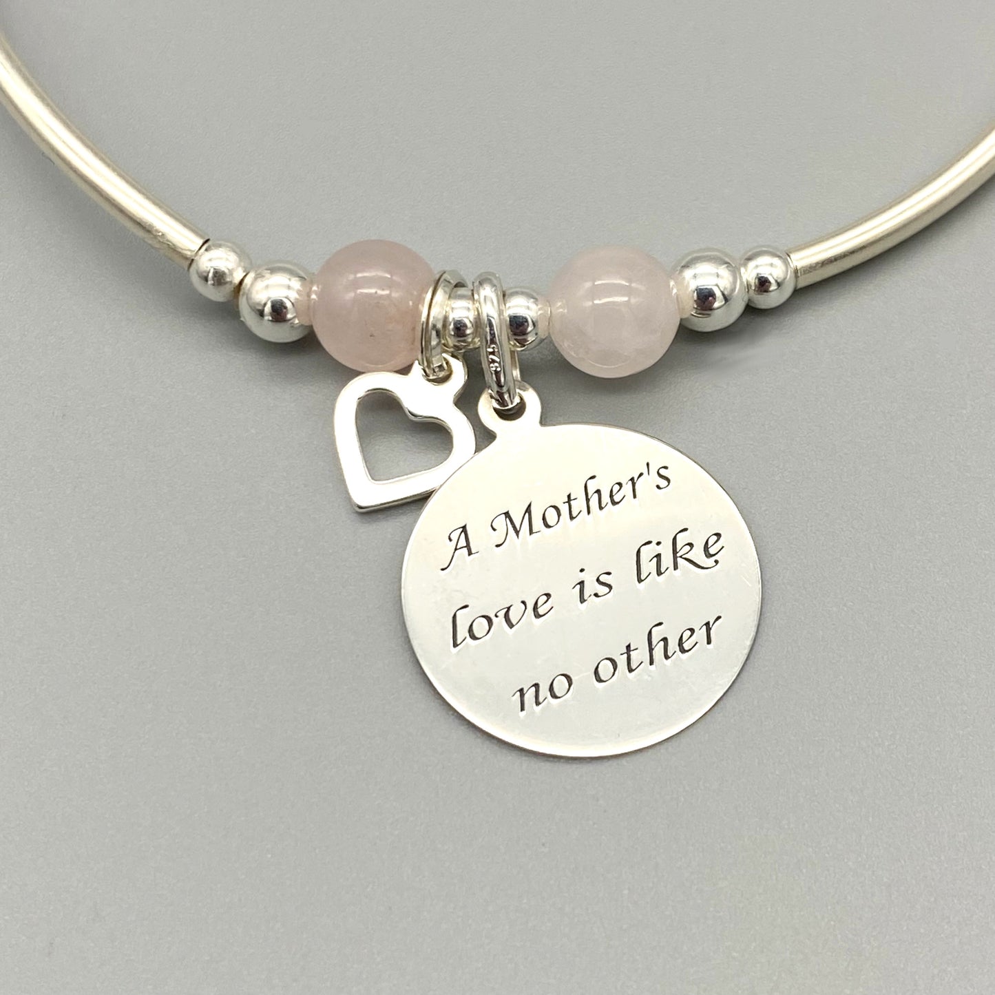 Closeup of "Mother's Love is Like No Other" heart charm silver rose quartz women's stacking bracelet by My Silver Wish