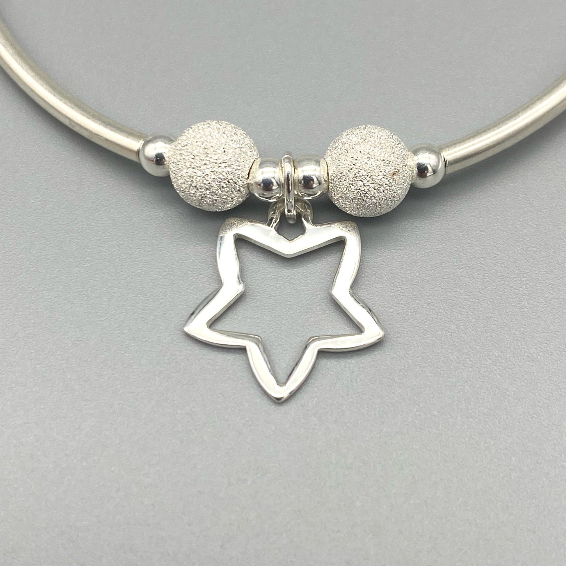 Closeup of Open Star charm women's sterling silver stacking bracelet by My Silver Wish