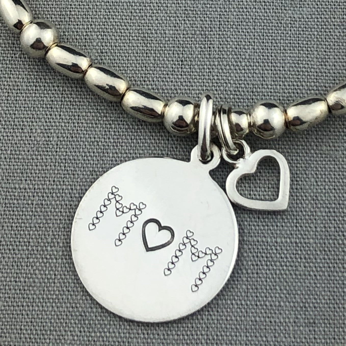 Closeup of "Mum" sterling silver hand-made women's stacking charm bracelet by My Silver Wish