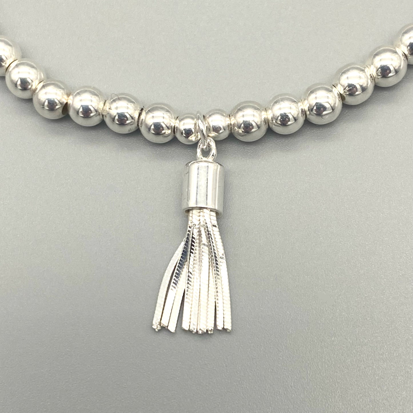 Closeup of Tassel charm sterling silver women's beaded stacking bracelet by My Silver Wish